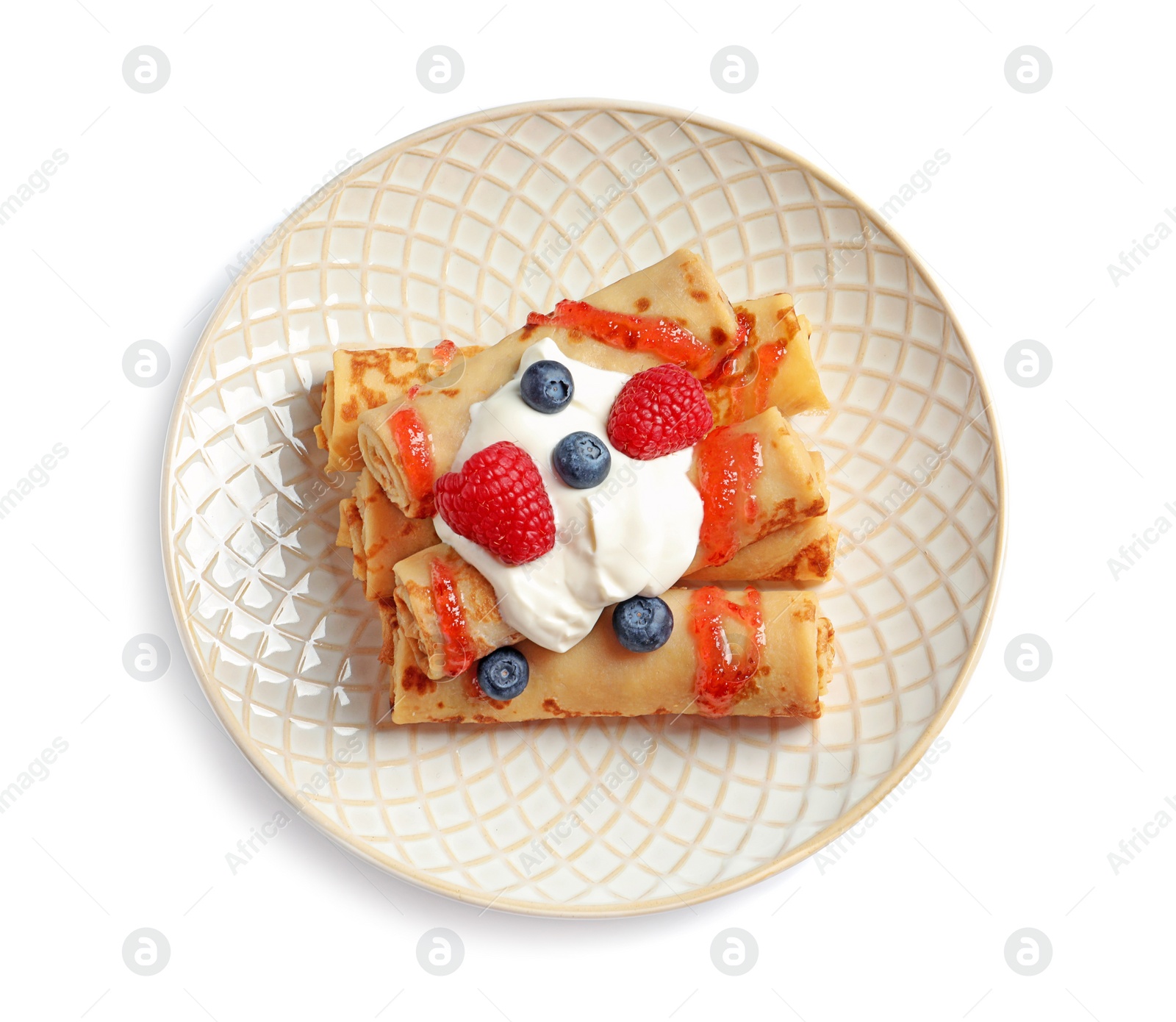 Photo of Thin pancakes with syrup, cream and berries on plate against white background, top view