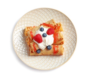 Thin pancakes with syrup, cream and berries on plate against white background, top view