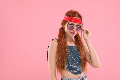 Photo of Stylish young hippie woman in sunglasses on pink background, space for text