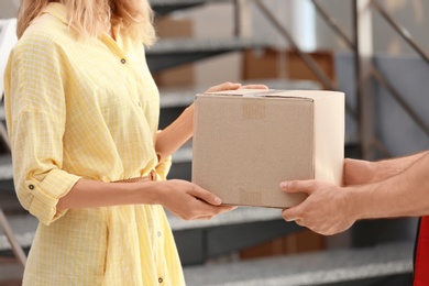 Photo of Woman receiving parcel from deliveryman on blurred background, closeup. Space for text