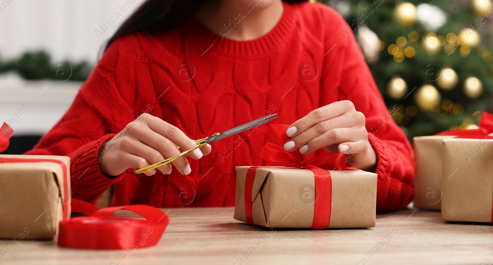 Photo of Woman decorating Christmas gift box at wooden table indoors, closeup