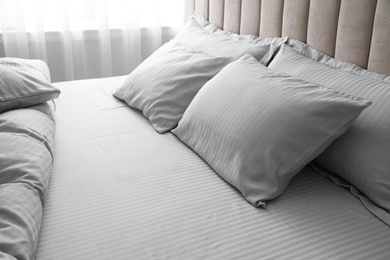 Photo of Comfortable bed with soft blanket and pillows indoors, closeup