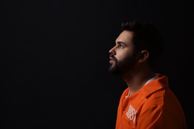 Photo of Prisoner in jumpsuit on black background, space for text
