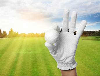Image of Player holding golf ball in park on sunny day, closeup. Space for design