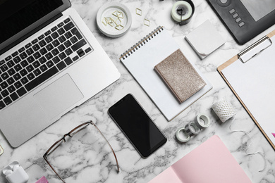 Photo of Flat lay composition with laptop, smartphone and stationery on marble table. Designer's workplace