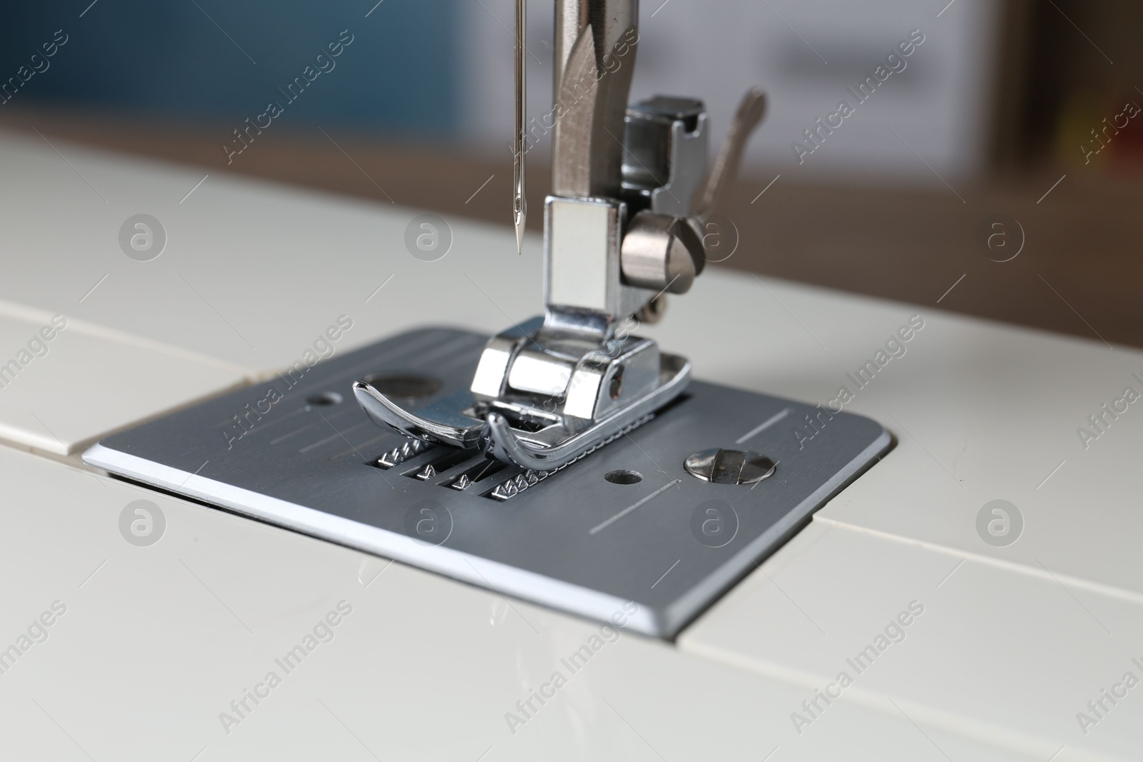 Photo of White sewing machine on blurred background, closeup