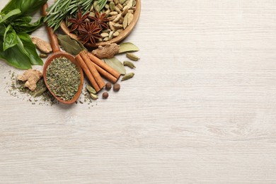 Different natural spices and herbs on light wooden table, flat lay. Space for text