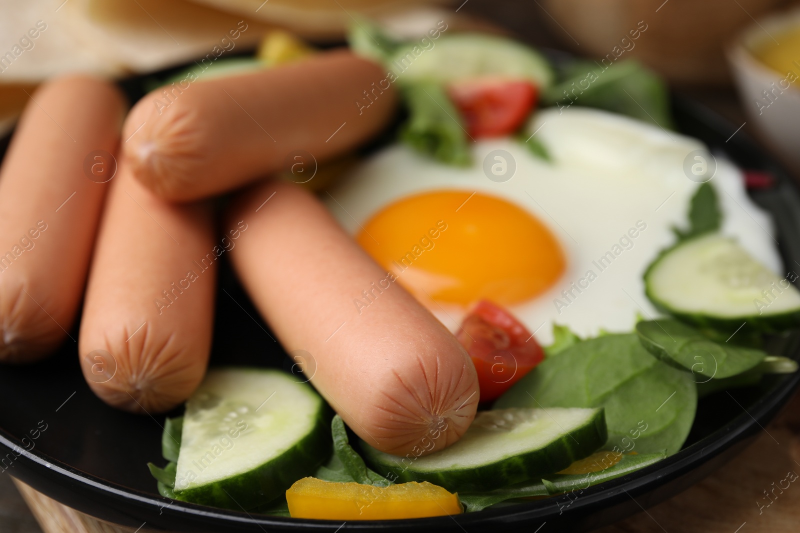 Photo of Delicious breakfast with boiled sausages and fried egg on wooden table, closeup