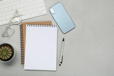 Photo of Flat lay composition with notebooks, smartphone, glasses and pen on light grey table