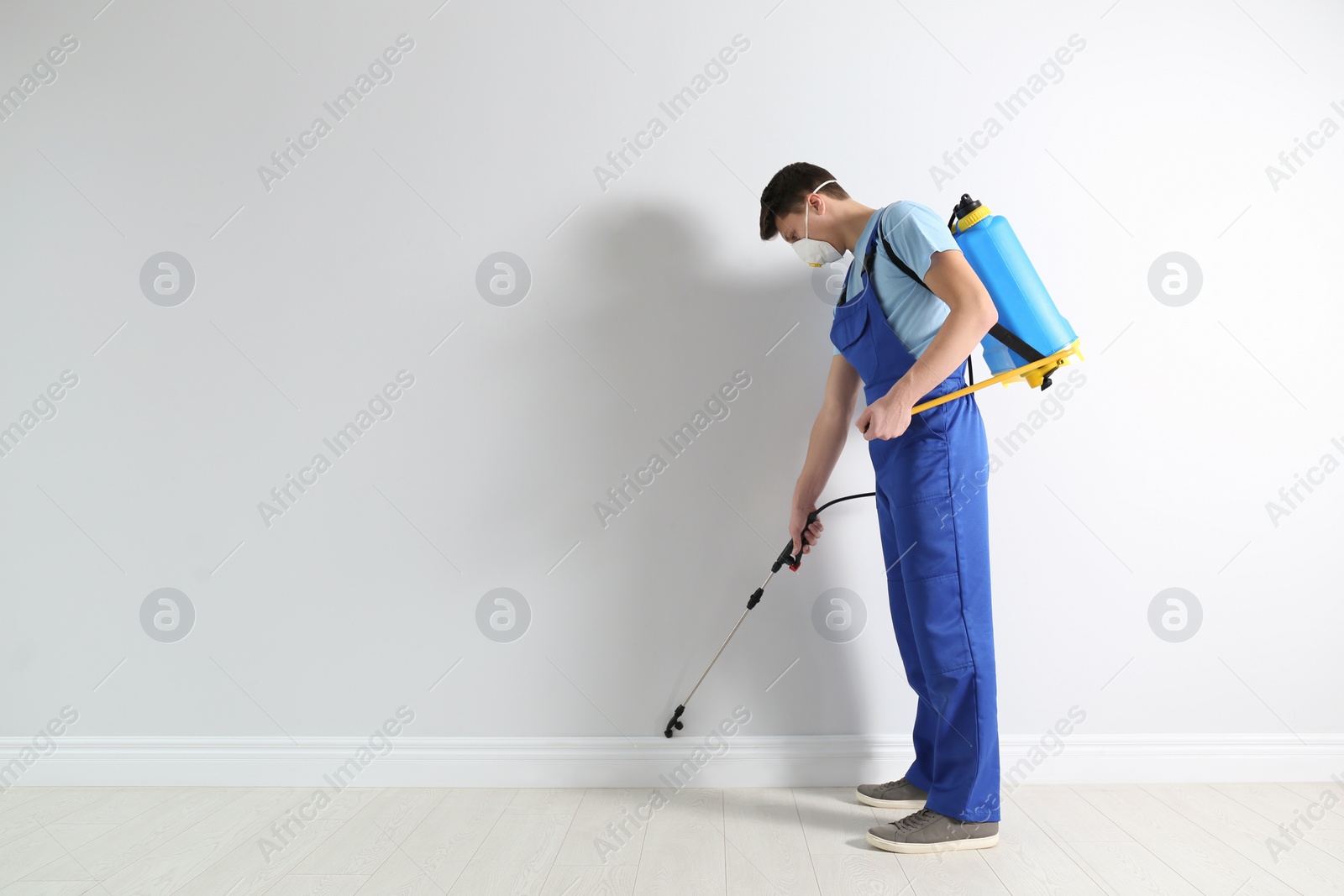 Photo of Pest control worker spraying pesticide in room. Space for text