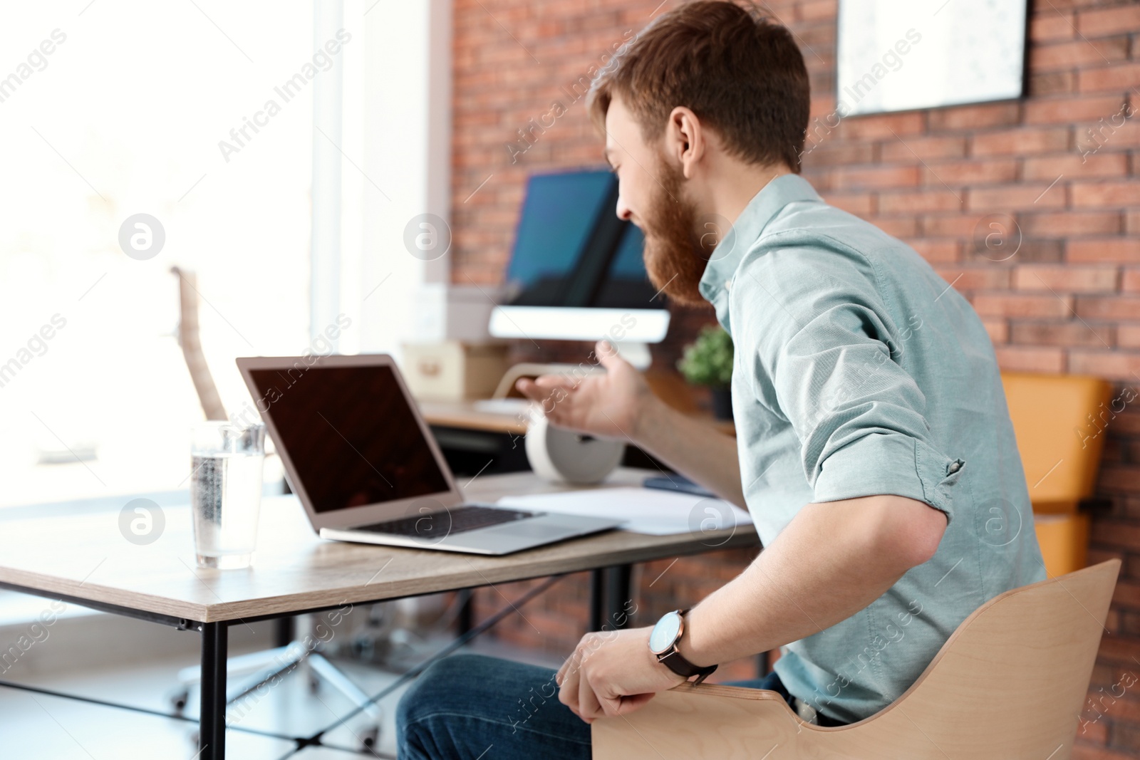 Photo of Young man using video chat on laptop in home office. Space for text