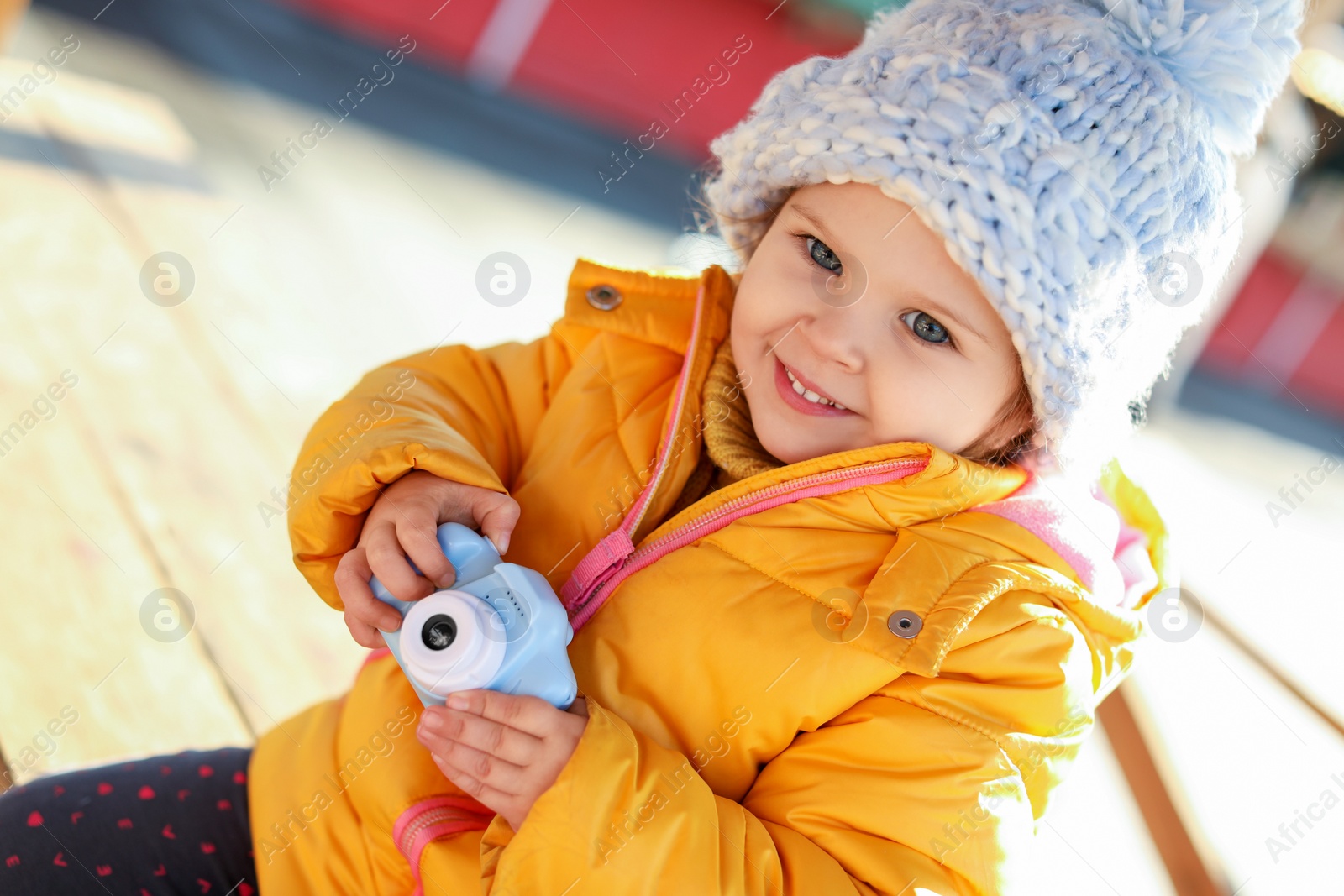 Photo of Cute little photographer with toy camera outdoors