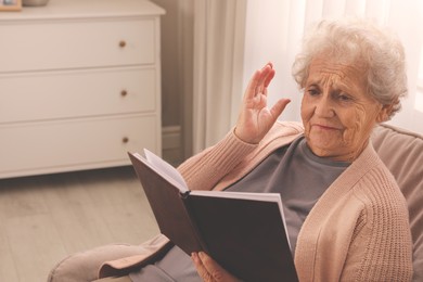 Photo of Senior woman with notebook at home, space for text. Age-related memory impairment