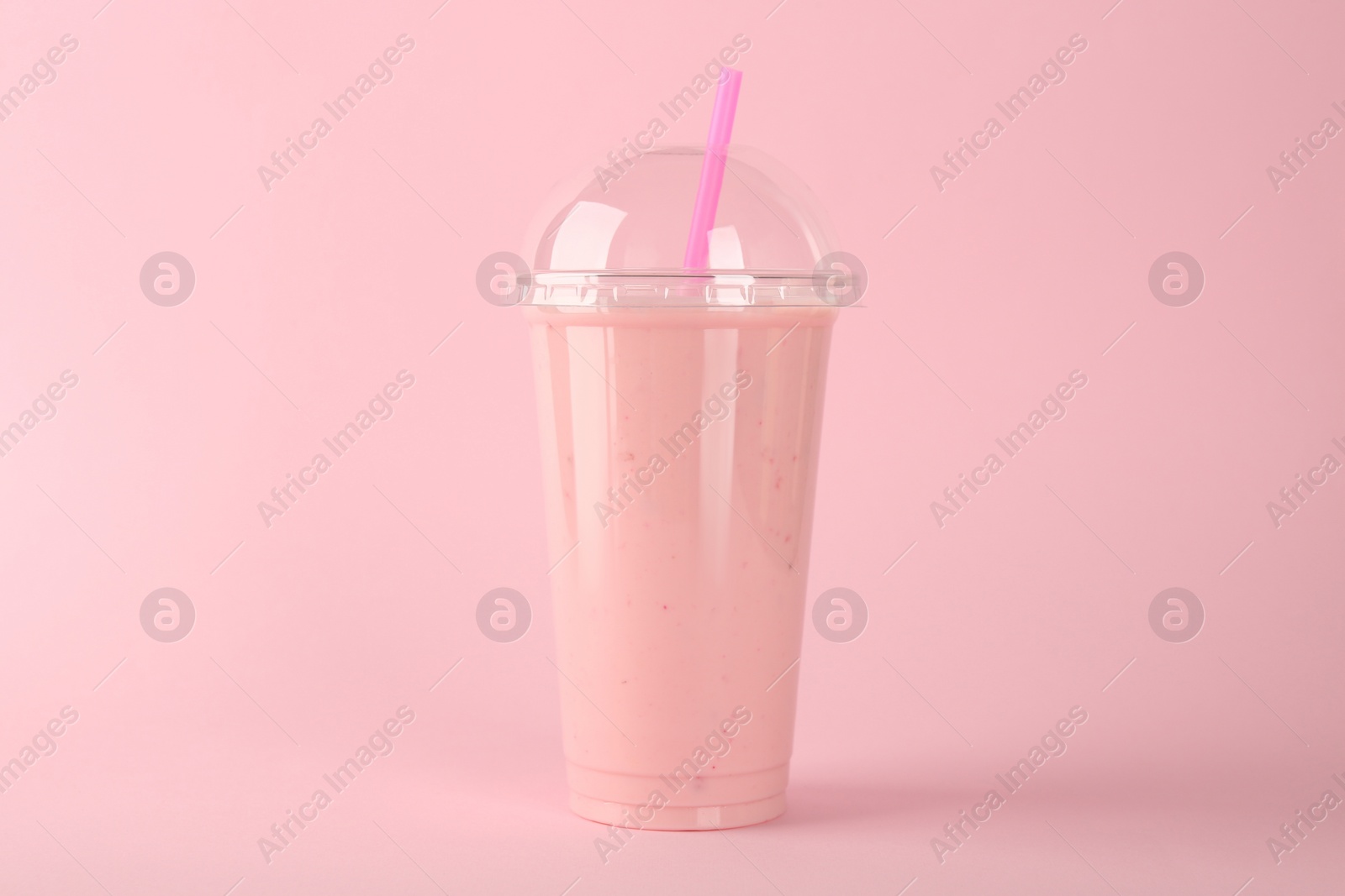 Photo of Plastic cup of tasty smoothie on pink background