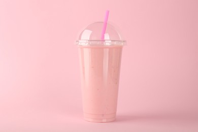 Photo of Plastic cup of tasty smoothie on pink background