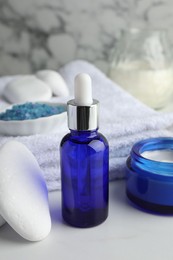 Photo of Spa composition. Cosmetic products, sea salt, towel and stone on white table