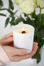 Woman holding burning candle with wooden wick, closeup