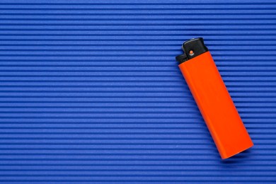 Photo of Stylish small pocket lighter on blue corrugated fiberboard, top view. Space for text