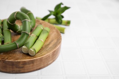 Photo of Pieces of beautiful green bamboo stems on white tiled table, closeup. Space for text