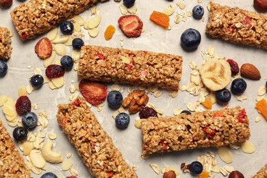 Tasty granola bars and ingredients on beige marble table, above view