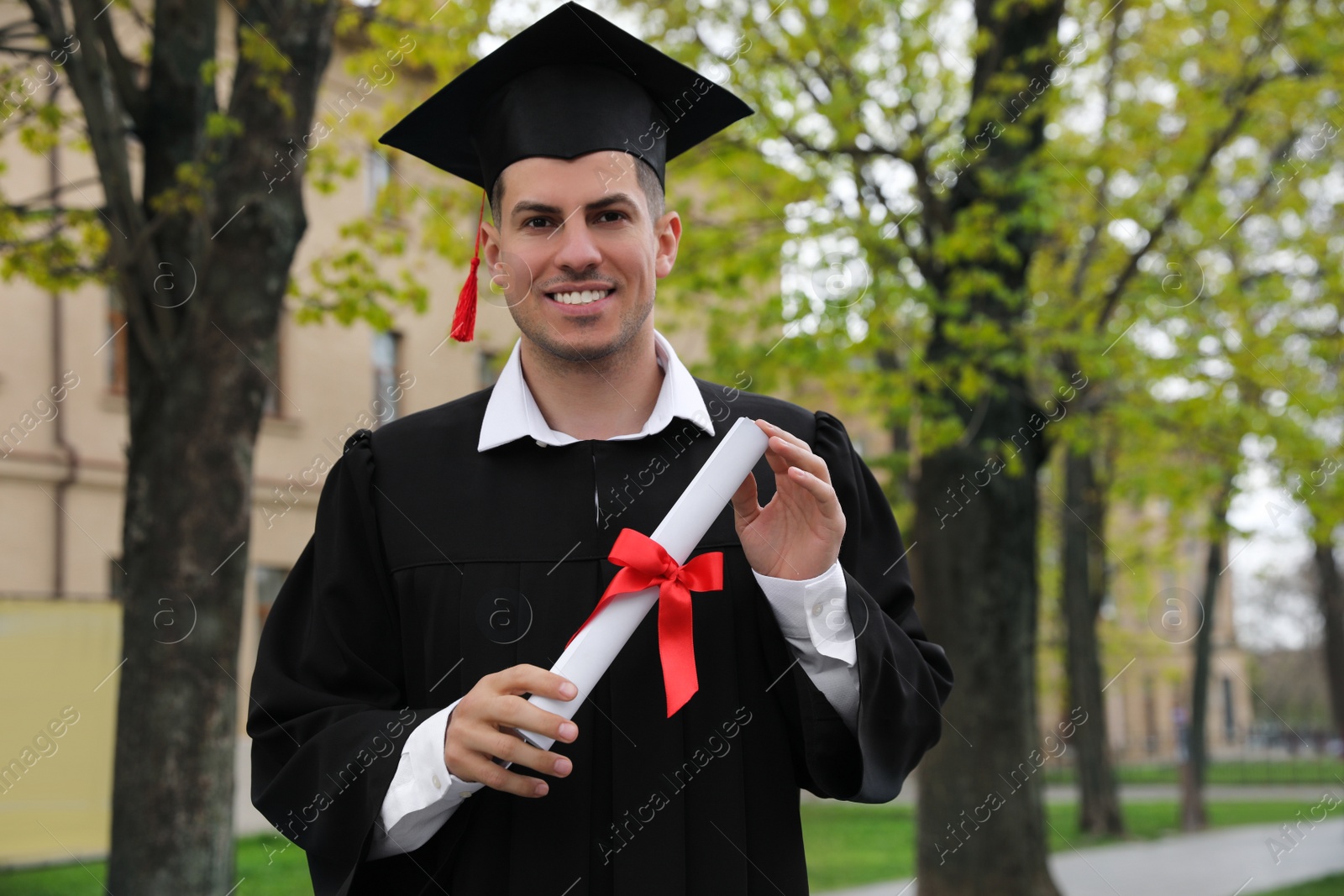 Photo of Happy student with diploma after graduation ceremony outdoors