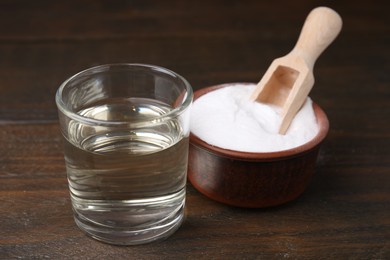 Vinegar in glass and baking soda on wooden table