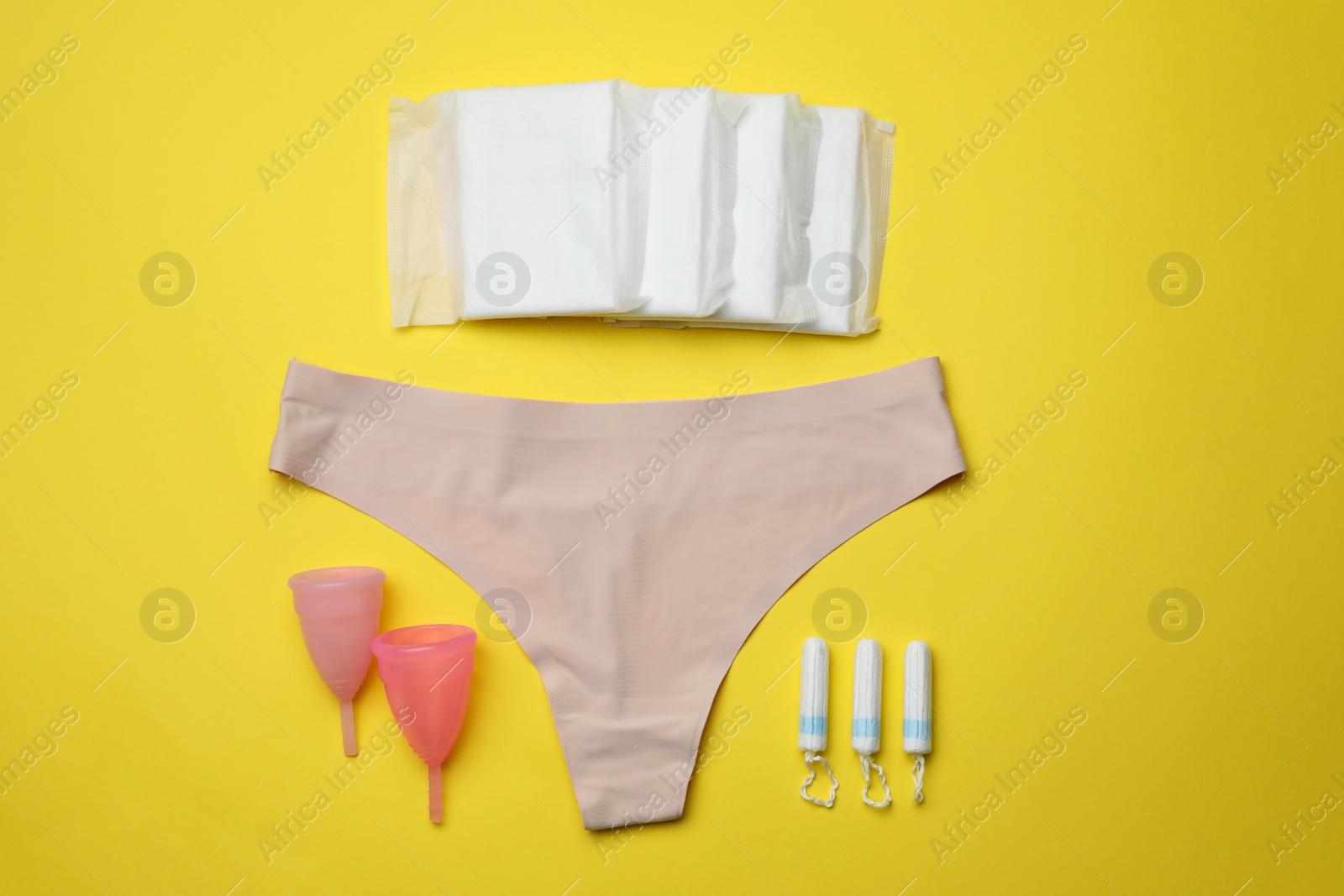 Photo of Flat lay composition with woman's panties and menstrual hygiene products on yellow background