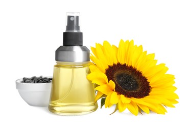 Photo of Spray bottle with cooking oil, sunflower and seeds on white background