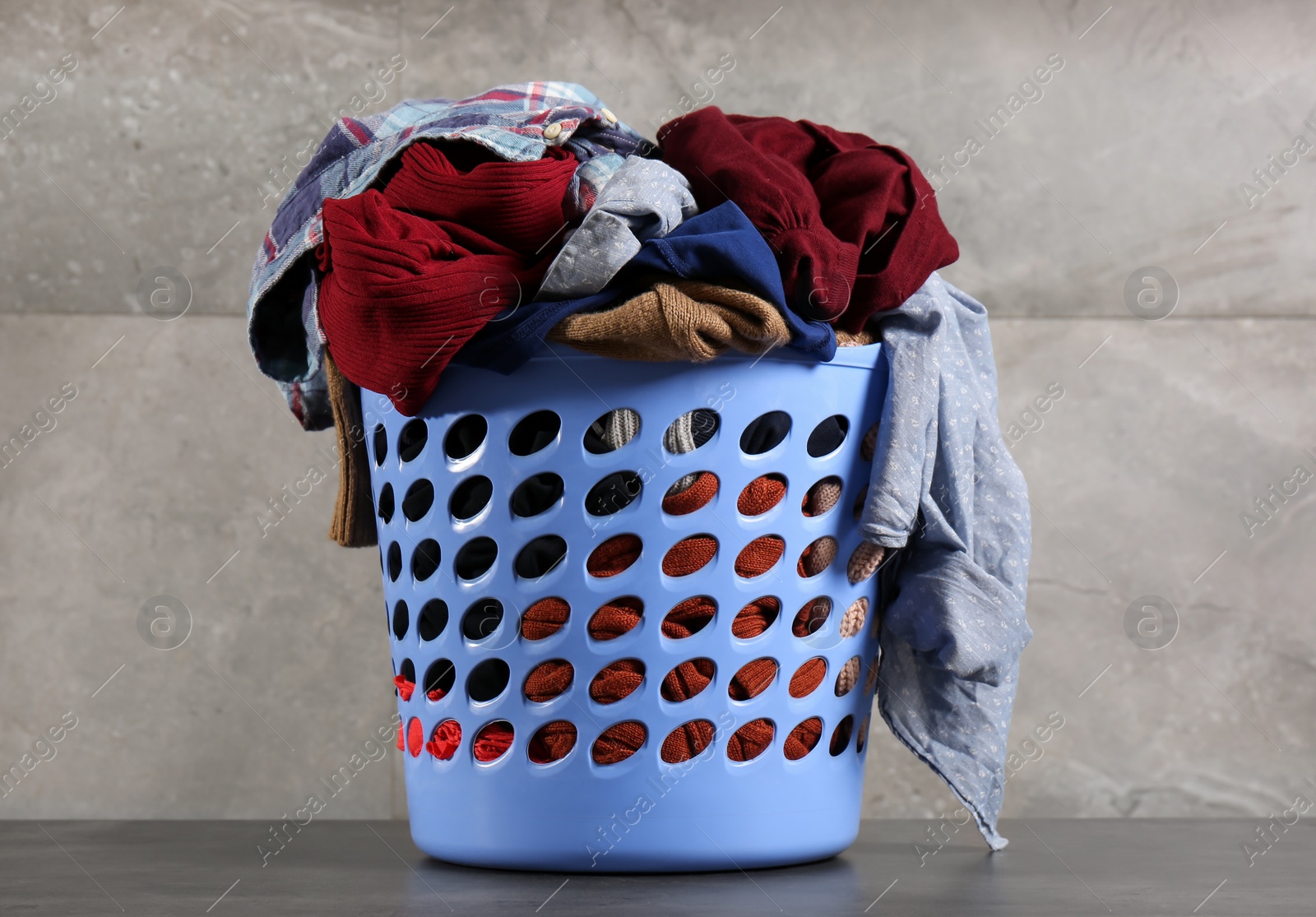 Photo of Laundry basket with clothes near grey wall