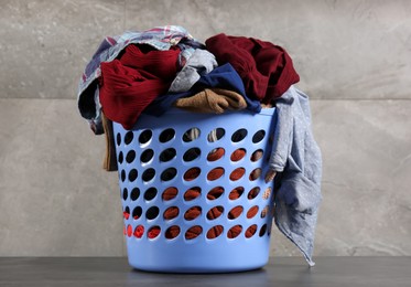 Laundry basket with clothes near grey wall