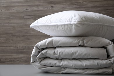 Soft folded blanket and pillow on light grey table, closeup