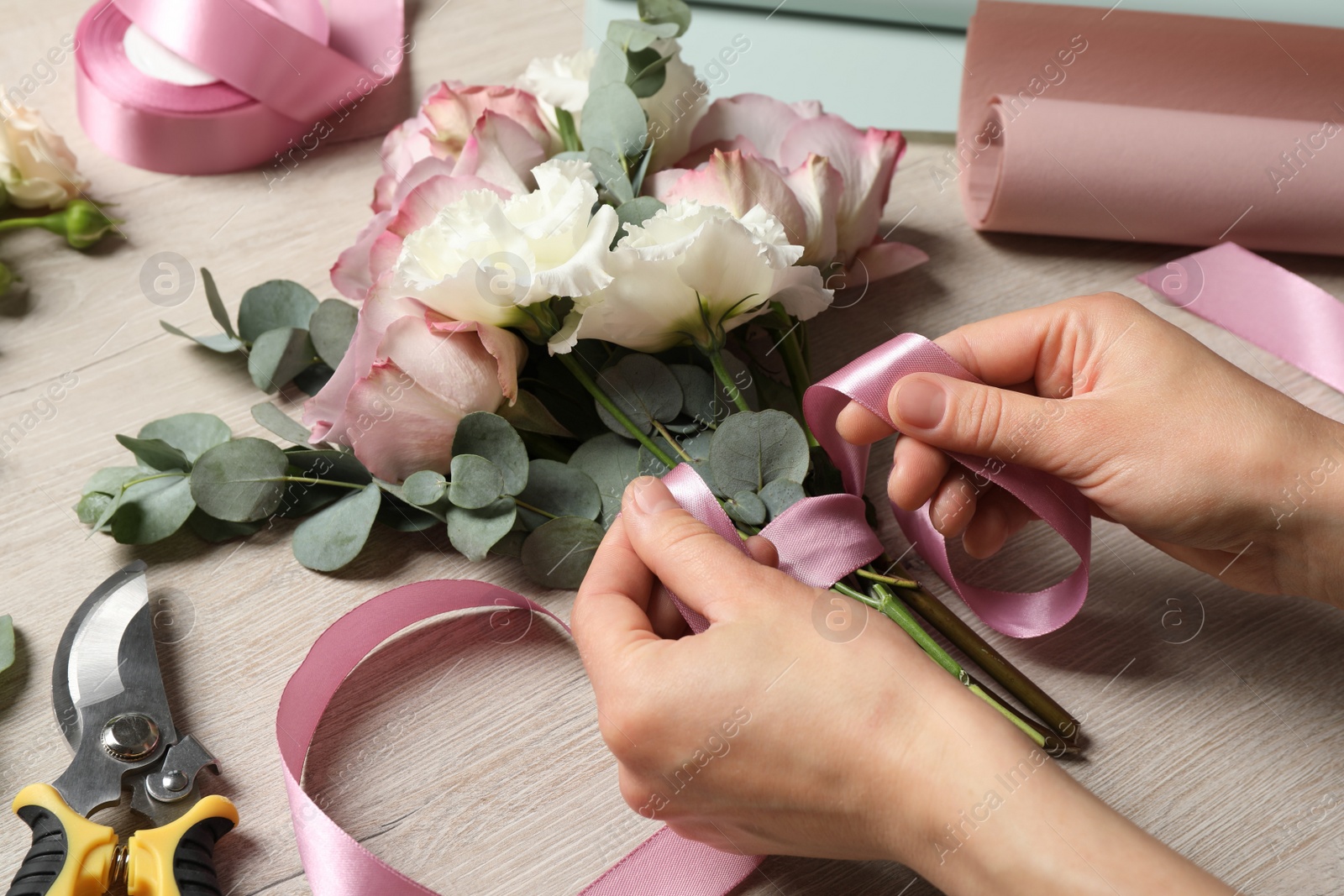 Photo of Florist creating beautiful bouquet at wooden table, closeup