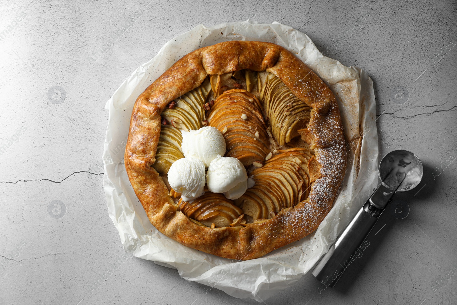 Photo of Delicious apple galette served with ice cream on light grey textured table, top view