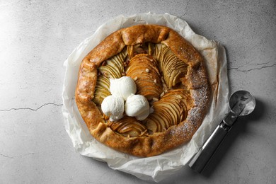 Delicious apple galette served with ice cream on light grey textured table, top view