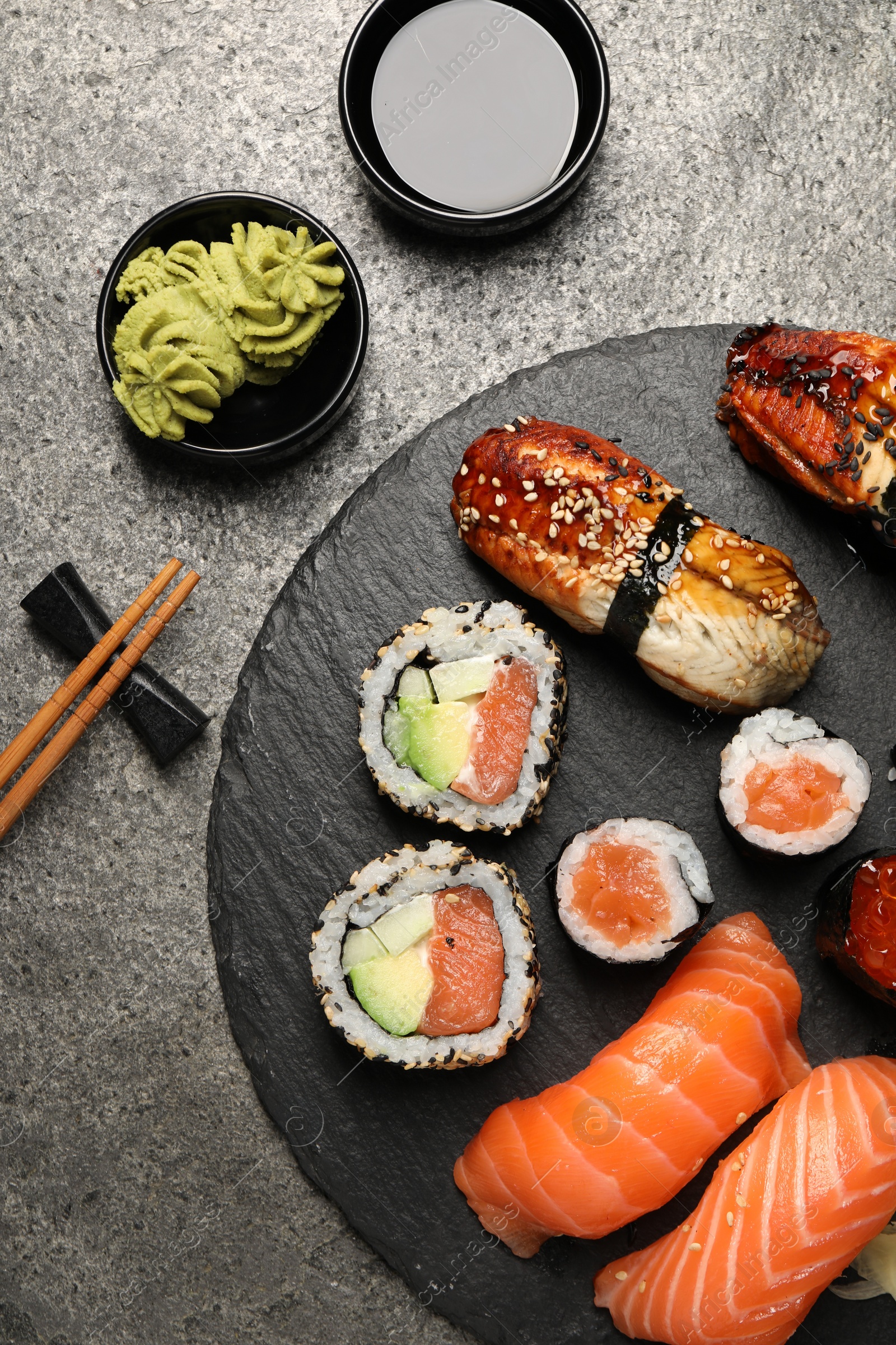 Photo of Set of delicious sushi rolls on dark grey table, flat lay