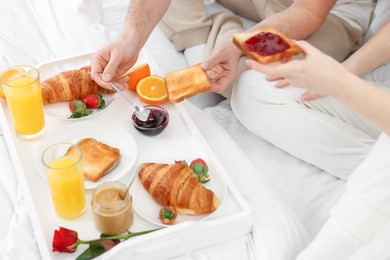 Photo of Couple eating tasty breakfast on bed, closeup