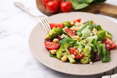 Photo of Healthy meal. Tasty salad with quinoa, chickpeas and vegetables served on white marble table, closeup