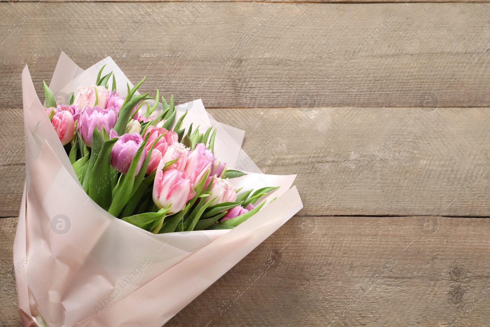 Photo of Bouquet of beautiful tulips on wooden table, top view. Space for text