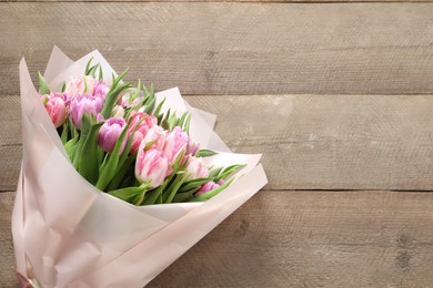 Photo of Bouquet of beautiful tulips on wooden table, top view. Space for text