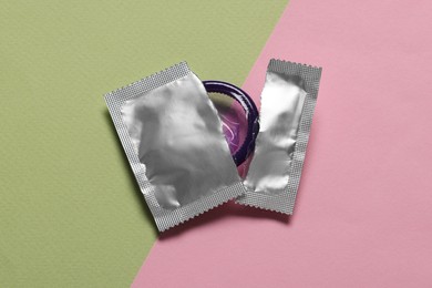 Photo of Condom in torn package on color background, top view. Safe sex
