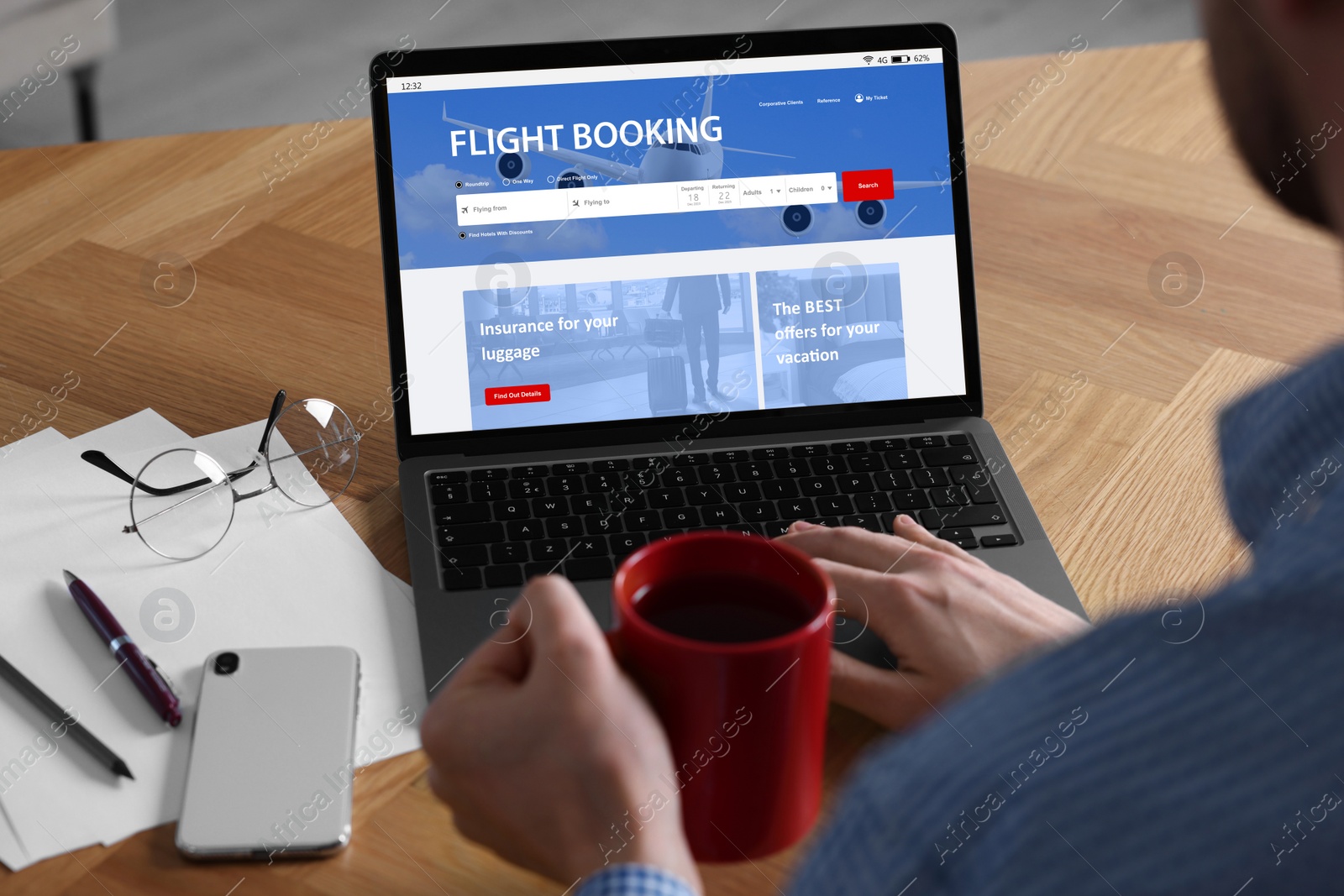 Image of Man using laptop to book flight at wooden table, closeup