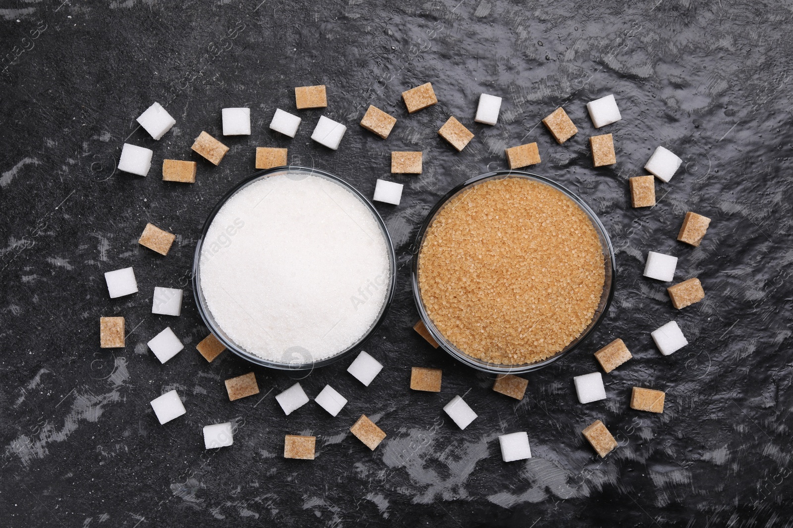 Photo of Different types of sugar in bowls on dark gray textured table, flat lay