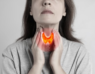 Woman and illustration of thyroid gland on grey background