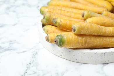 Photo of Many raw yellow carrots on white marble table, closeup