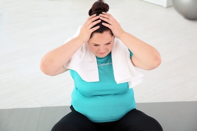 Tired overweight woman with towel at home