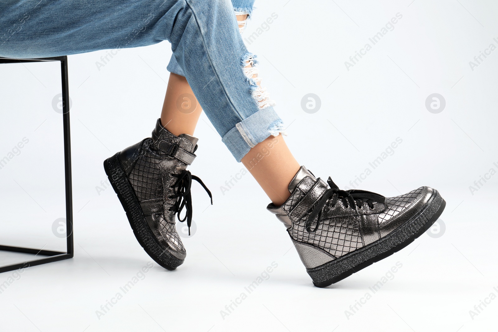 Photo of Woman in stylish shoes sitting on stool, white background