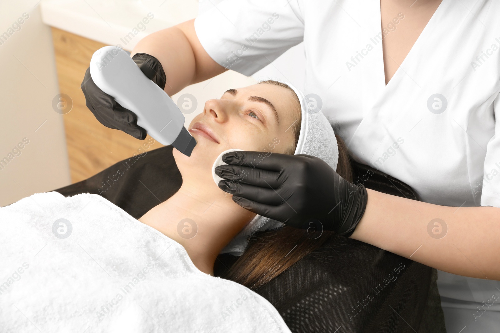 Photo of Cosmetologist using ultrasonic scrubber, closeup. Client having cleansing procedure in clinic