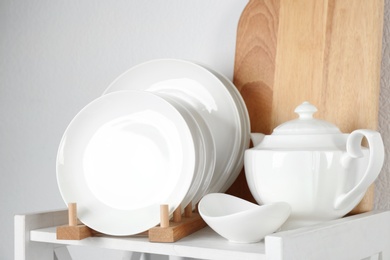 Photo of Different clean tableware on shelf in kitchen