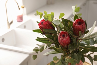 Bouquet of beautiful protea flowers in kitchen, closeup. Interior design