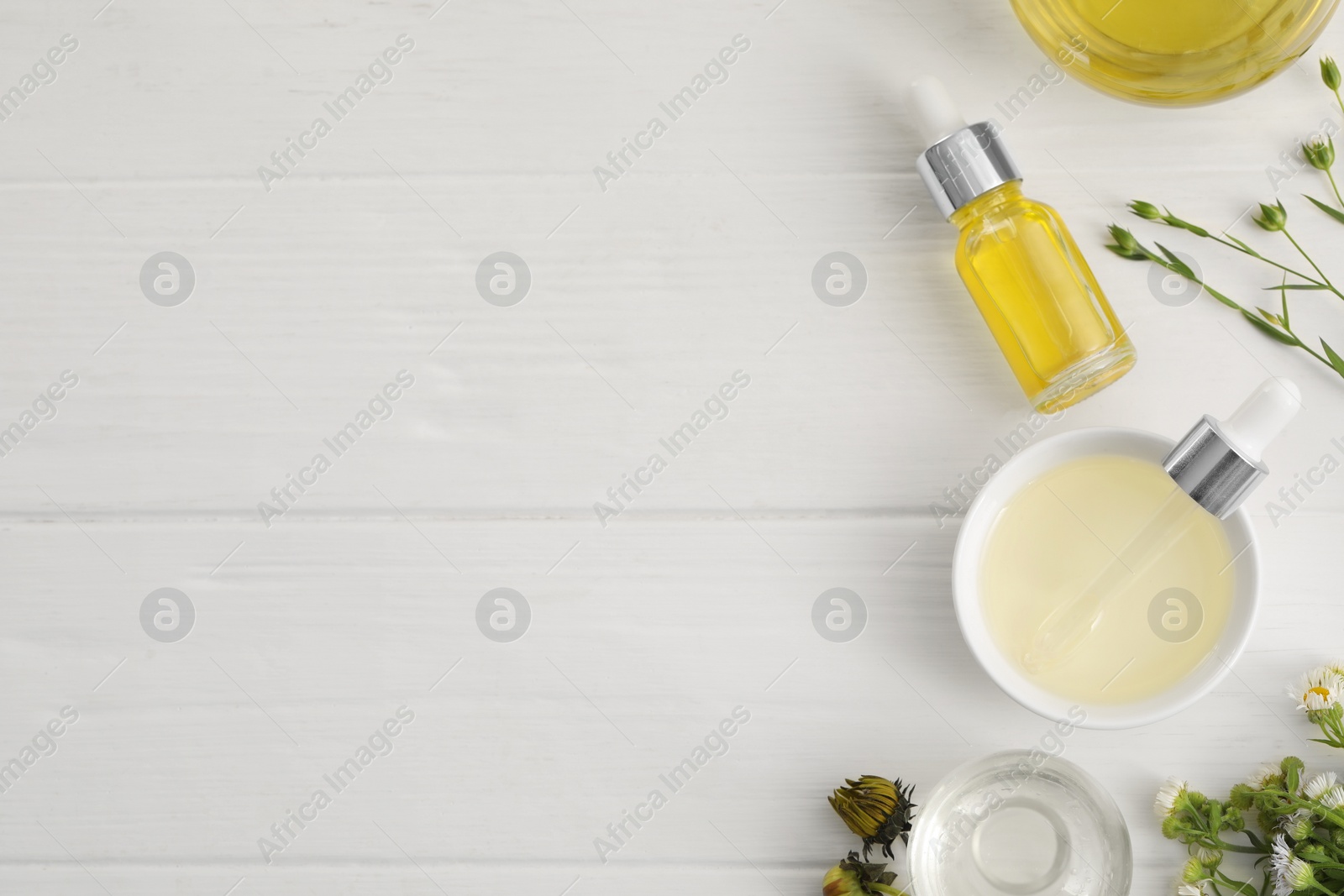 Photo of Cosmetic oil and flowers on white wooden table, flat lay. Space for text